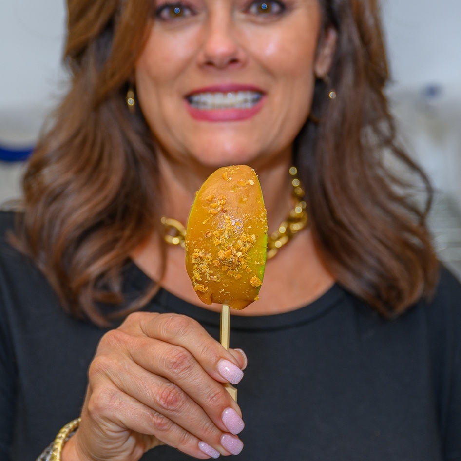 A woman holds a carmel apple